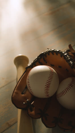 Vertical-Video-Close-Up-Studio-Baseball-Still-Life-With-Wooden-Bat-And-Ball-In-Catchers-Mitt-On-Wooden-Floor